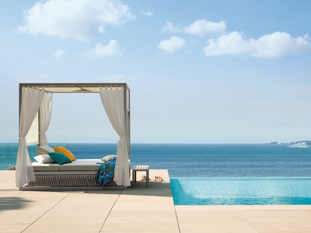 Un pat cu baldachin in aer liber