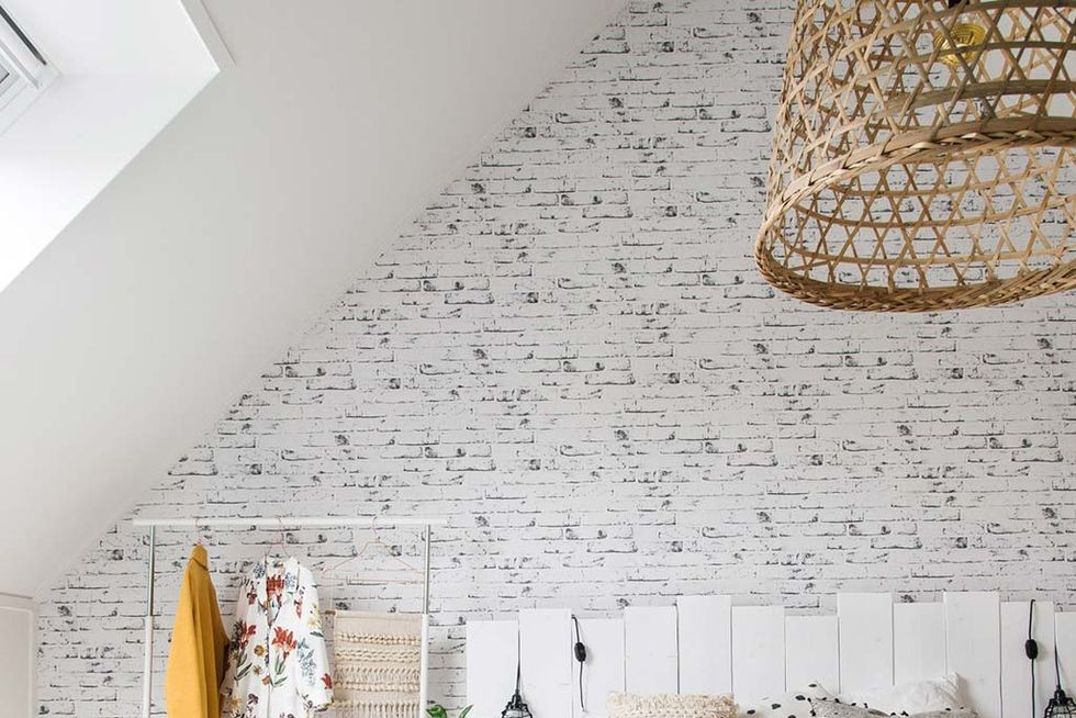 dormitor cu perete de caramida si tablie din lemn